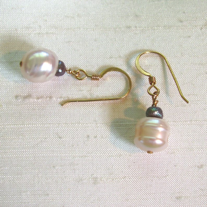 May include: A pair of gold earrings with white pearl and dark gray gemstone accents.