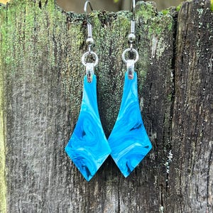 May include: A pair of blue and white marbled diamond-shaped earrings with silver hooks.