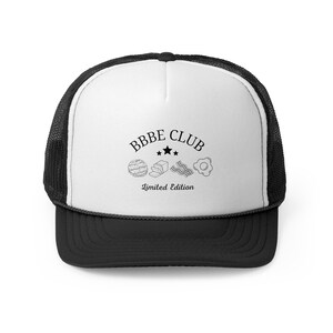 May include: Black and white trucker hat with a white front panel and a black mesh back. The front panel features the text "BBBE CLUB" in black lettering with a graphic of four breakfast foods and the text "Limited Edition".