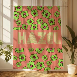 May include: A coral pink shower curtain with a green frog pattern. The frogs are holding hearts and the name "HAZEL" is written in a yellow striped font.
