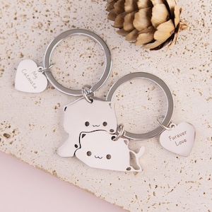 Può includere: Due portachiavi argentati con ciondoli a forma di gatto. Un ciondolo dice "My Catmate" e l'altro dice "Forever Love".