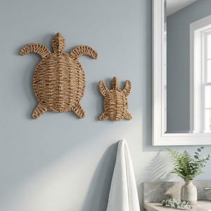 a bathroom with a large mirror, a towel rack, and two woven turtle-shaped wall decorations.