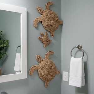 a bathroom with a mirror, towel rack, and three woven turtle-shaped wall decorations.