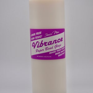 May include: A tall, cylindrical plastic bottle filled with an opaque, off-white liquid. The label is purple with white text reading Janice Mae Vibrance Paper Bead Glaze, Odor Free, Non-Toxic, and Net Contents: 16-oz (473.2 ml).