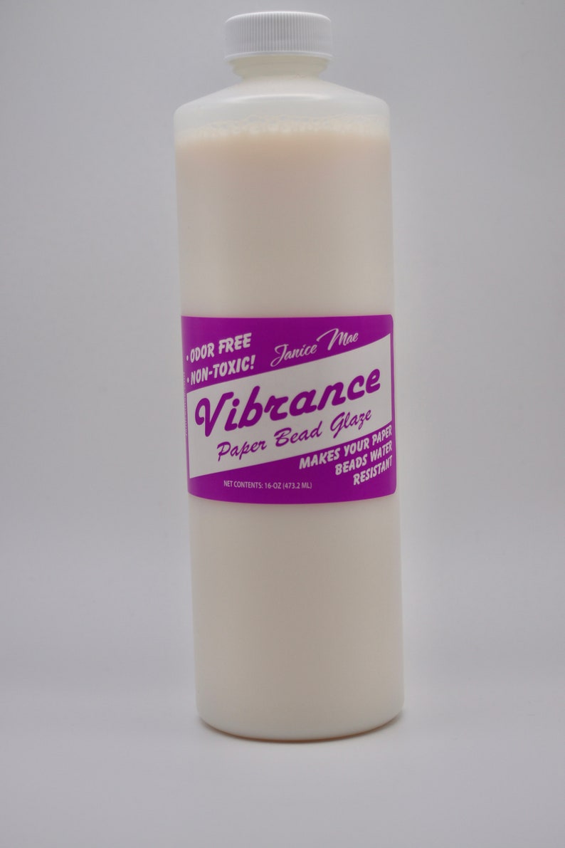 May include: A tall, cylindrical plastic bottle filled with an opaque, off-white liquid. The label is purple with white text reading Janice Mae Vibrance Paper Bead Glaze, Odor Free, Non-Toxic, and Net Contents: 16-oz (473.2 ml).