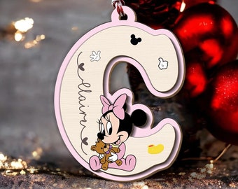 Op de afbeelding: Een lichtroze en beige houten ornament in de vorm van de letter C, voorzien van een tekenfilmmuis die een bruine teddybeer vasthoudt. De naam Claire staat verticaal in zwarte letters gedrukt. Inclusief een rood-wit gedraaid ophangkoord.