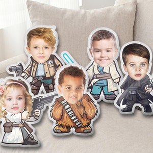 Op de afbeelding: Vijf witte kussens met cartoonfiguren. Elk kussen heeft een ander personage, waaronder een Chewbacca, een Stormtrooper, een Jedi en twee andere personages. De gezichten van de personages zijn vervangen door foto's van kinderen.