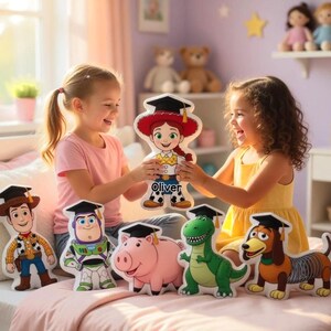 May include: Two young girls are holding up a cartoon character cutout that says "Oliver". The cutout is of a character from the Toy Story movie series. Other Toy Story character pillows are on the bed, including Woody, Buzz Lightyear, Rex, Hamm, and Slinky Dog.
