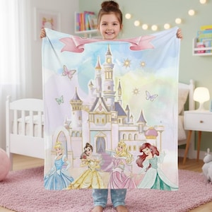 K&ouml;nnte beinhalten: Eine hellblaue Decke mit einer Aquarellillustration eines M&auml;rchenschlosses und vier Prinzessinnen. Die Decke hat ein rosa Banner und Schmetterlinge. Die Prinzessinnen tragen Kleider in Blau, Gelb und Rosa.