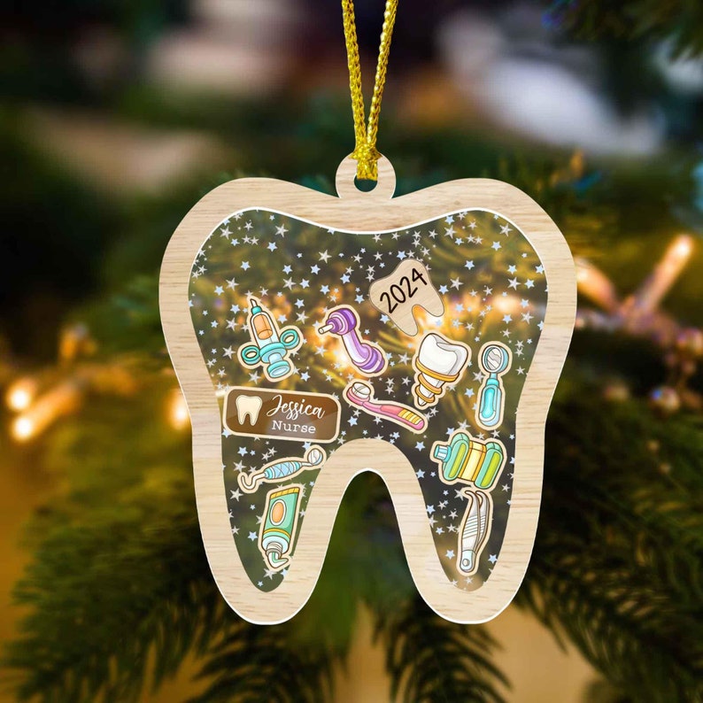 May include: Wooden Christmas ornament shaped like a tooth, featuring dental tools and the text "2024." The ornament includes the name "Jessica Nurse" and is decorated with star-shaped confetti.