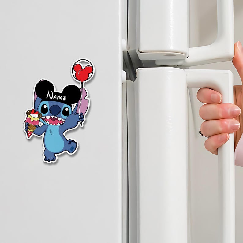May include: A blue cartoon character magnet holding an ice cream cone and a heart-shaped balloon. The character has large ears and the word "Name" is written on its head. The magnet is attached to a white refrigerator.