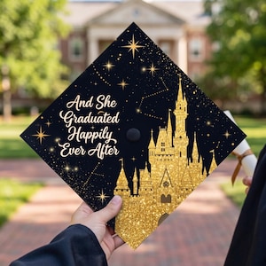 May include: A black graduation cap with gold glitter details and the text "And She Graduated Happily Ever After." The design features a gold castle and star constellations.