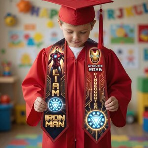 Może przedstawiać: Czerwona toga i czapka absolwenta z motywem Iron Mana. Szarfa zawiera logo Iron Mana, imię "Liam" oraz napis "Kindergarten Graduate 2026". Toga posiada zamek błyskawiczny.