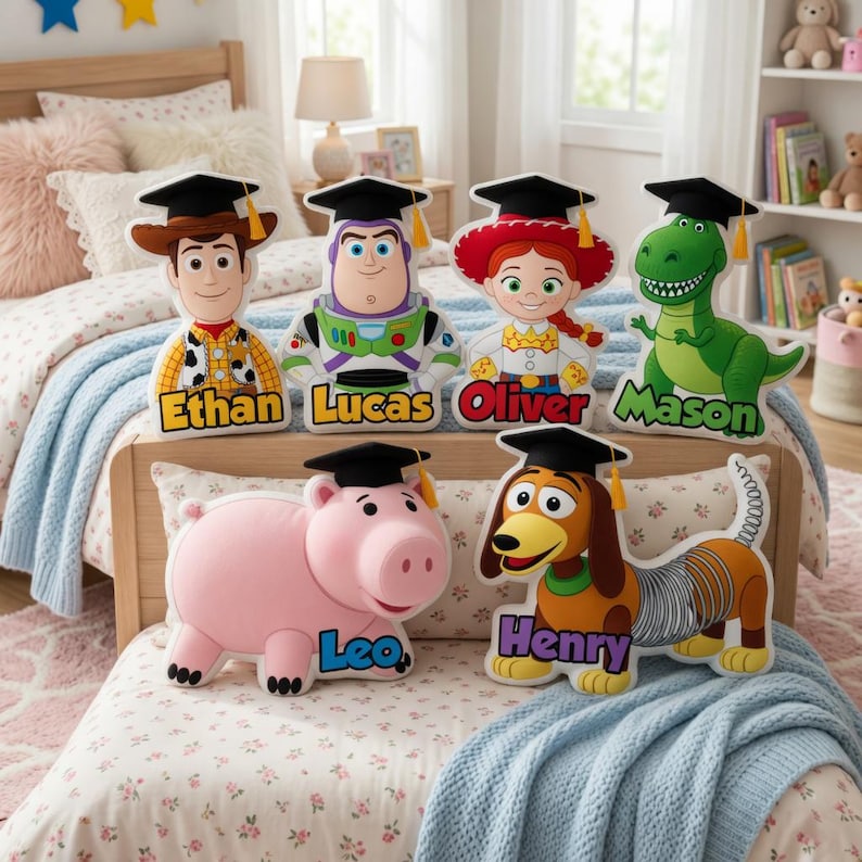 May include: A collection of Toy Story character-shaped pillows, each wearing a graduation cap and personalized with a name. The characters include Woody, Buzz Lightyear, Jessie, Rex, Hamm, and Slinky Dog. The pillows are displayed on a bed with floral bedding.