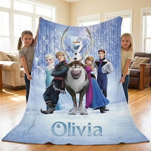 Puede incluir: Una manta azul claro con personajes de la pel&iacute;cula animada Frozen, incluyendo a Elsa, Anna, Kristoff, Olaf y Sven. La manta tiene un fondo de bosque invernal y el nombre "Olivia" en la parte inferior.