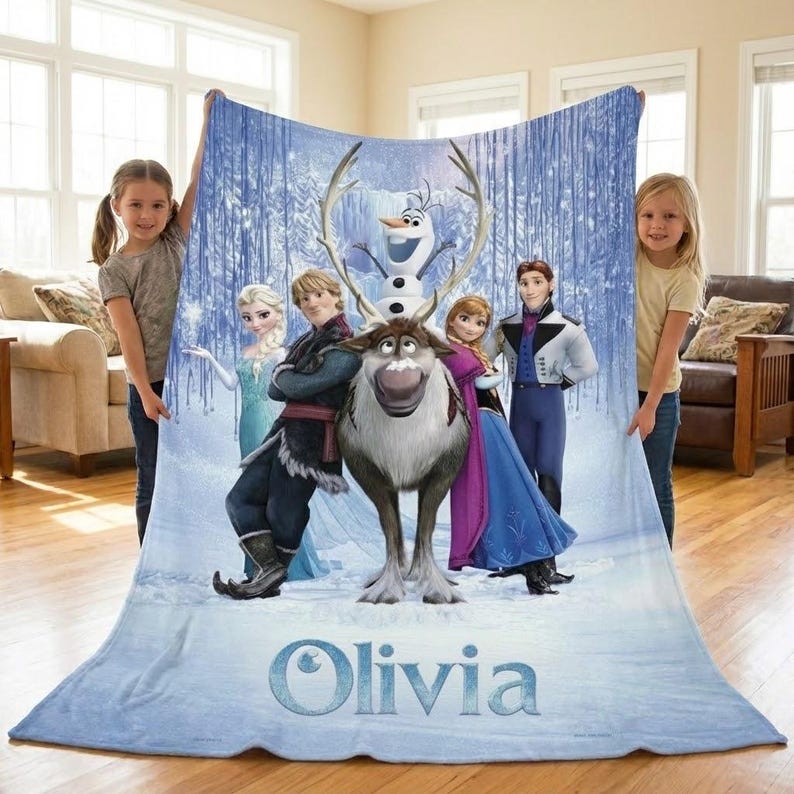 Puede incluir: Una manta azul claro con personajes de la pel&iacute;cula animada Frozen, incluyendo a Elsa, Anna, Kristoff, Olaf y Sven. La manta tiene un fondo de bosque invernal y el nombre "Olivia" en la parte inferior.