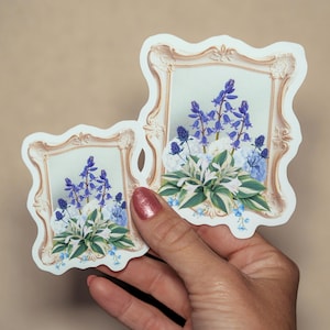 May include: Two die-cut stickers featuring a vintage-style ornate beige picture frame containing a botanical illustration of blue bell-shaped flowers, spiky purple thistle-like blooms, and green and white variegated hosta leaves.