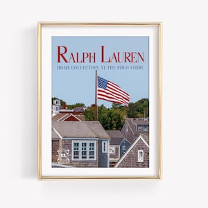 Pode incluir: Impressão emoldurada com o texto "Ralph Lauren Home Collection at The Polo Store". A imagem mostra uma bandeira americana tremulando sobre casas, com um céu azul ao fundo. A moldura tem um acabamento dourado.