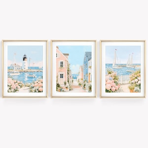 Peut inclure: Ensemble de trois impressions encadrées à l'aquarelle représentant des scènes côtières. Les impressions représentent un phare, une rue pittoresque avec des maisons colorées et des voiliers. Chaque impression est encadrée dans un cadre doré et comprend des fleurs roses et blanches.