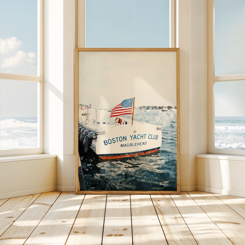 May include: Framed print of a boat with an American flag, docked in the water. The boat is labeled "Boston Yacht Club Marblehead." The print is in a wooden frame and is displayed in a room with large windows and a wooden floor.