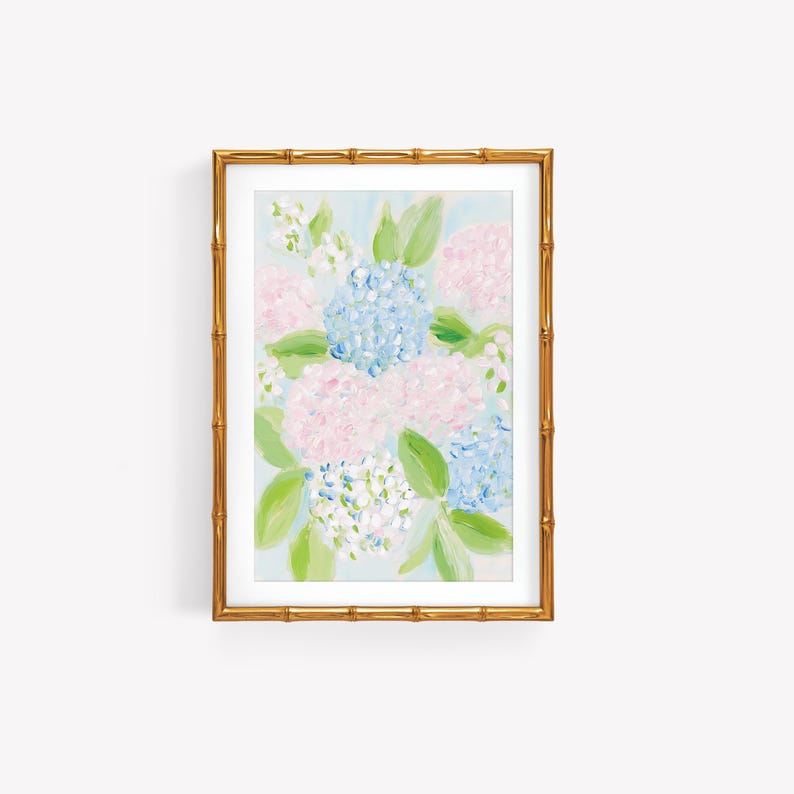 May include: A framed painting of hydrangea flowers in shades of light blue, soft pink, and white, accented with green leaves. The artwork is enclosed in a metallic gold frame with a textured bamboo-style design and a white mat border.
