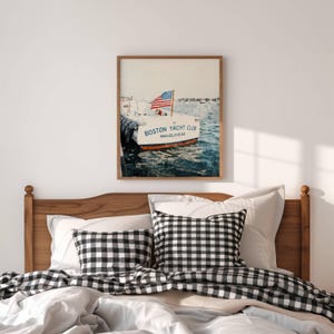 May include: A framed print featuring a boat with an American flag. The boat is labeled "Boston Yacht Club Marblehead." The print is displayed above a bed with a wooden headboard, white bedding, and black and white checkered pillows.