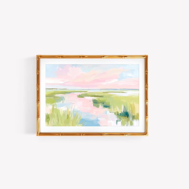 Op de afbeelding: Een landschapsschilderij in een gouden lijst in bamboestijl met een moeraslandschap met zachtroze wolken, lichtblauw water en felgroen gras. Het kunstwerk gebruikt losse penseelstreken om een serene kustwaterweg bij zonsondergang weer te geven.