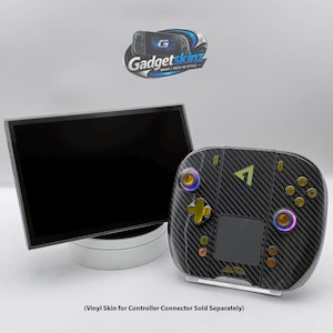 May include: A black carbon fibre textured vinyl skin applied to a handheld gaming controller with gold buttons and a black screen display. The Gadgetskinz logo is visible at the top. Text at the bottom reads: Vinyl Skin for Controller Connector Sold Separately.