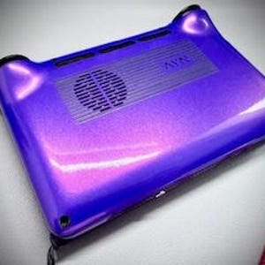 May include: A glossy, purple electronic device with a vent and speaker. The device has rounded corners and a textured surface. The word "AVN" is visible on the top. The device is on a white surface.