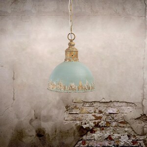 May include: A vintage-style pendant light with a distressed, light blue dome shade and a rusty gold-colored top. The light hangs from a chain, showcasing an industrial or farmhouse aesthetic. The shade has a weathered appearance, adding to its antique charm.