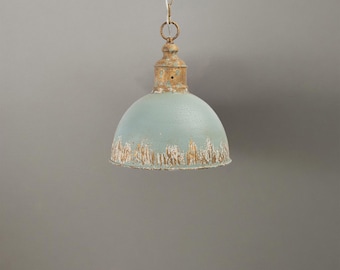 May include: A vintage pendant light with a distressed finish. The light fixture has a pale blue, dome-shaped shade with a weathered, off-white and gold trim. It hangs from a chain, offering a rustic, industrial aesthetic.