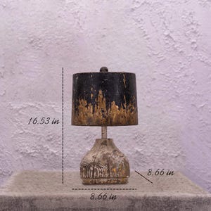 May include: A rustic table lamp with a black and gold painted lampshade and a wooden base. The lamp is 16.53 inches tall and the base is 8.66 inches wide.