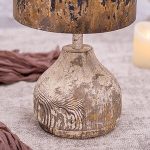 May include: A rustic wooden lamp base with a distressed white and gold finish. The base has a round, bulbous shape with a textured wood grain pattern.