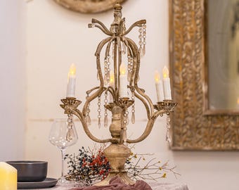 May include: A gold metal candelabra with five candle holders and crystal accents. The candelabra is decorated with a distressed finish and has a vintage style.