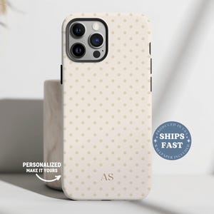 May include: A beige phone case with a repeating pattern of small, light brown polka dots. The case has a black border and a camera cutout. The initials "AS" are at the bottom. Text on the case says "Personalized Make It Yours" and "Ships Fast".