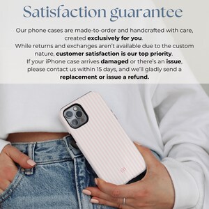 May include: A pink and white striped iPhone case with a subtle texture. The case has a small logo on the bottom right corner. The case is being held by a person's hand.
