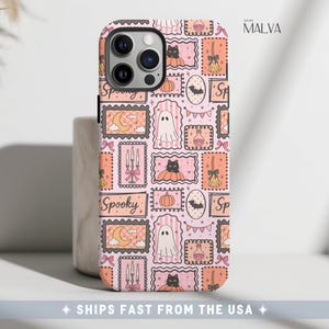 Puede incluir: Una funda para tel&eacute;fono con un patr&oacute;n repetitivo de marcos rectangulares sobre un fondo rosa claro. Los marcos contienen ilustraciones de fantasmas, gatos negros en calabazas, lunas crecientes, velas, escobas y pociones con la palabra Spooky.