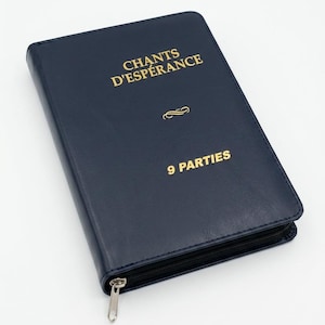 May include: A navy blue book with gold lettering that reads "CHANTS D'ESPÉRANCE" and "9 PARTIES". The book has a zipper closure and a simple design. The book is closed and appears to be new.