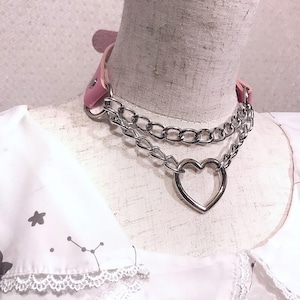 May include: A pink leather choker with a silver chain and a large heart charm.