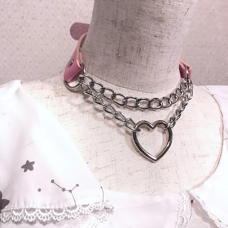 May include: A pink leather choker with a silver chain and a large heart charm.