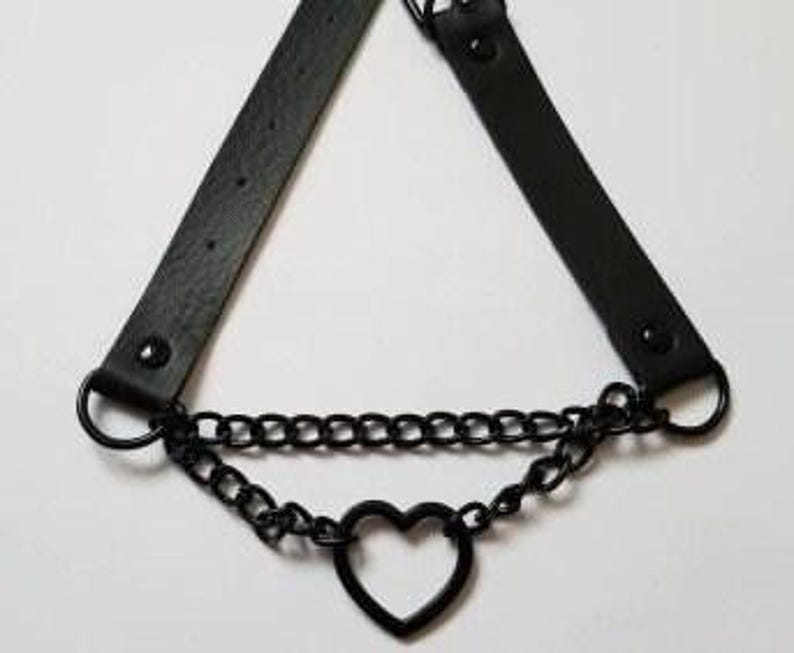 May include: Black leather choker necklace with a black metal chain and a heart-shaped pendant.