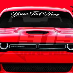 May include: A red Dodge Challenger with the text "Your Text Here" on the windshield. The car has a black grille and black headlights.
