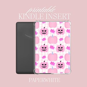Puede incluir: Inserción imprimible para Kindle Paperwhite con un patrón de cuadros rosa y blanco con calabazas rosas con ojos negros y una boca sonriente. El texto "printable KINDLE INSERT" está en la parte superior de la imagen y "PAPERWHITE" en la parte inferior.
