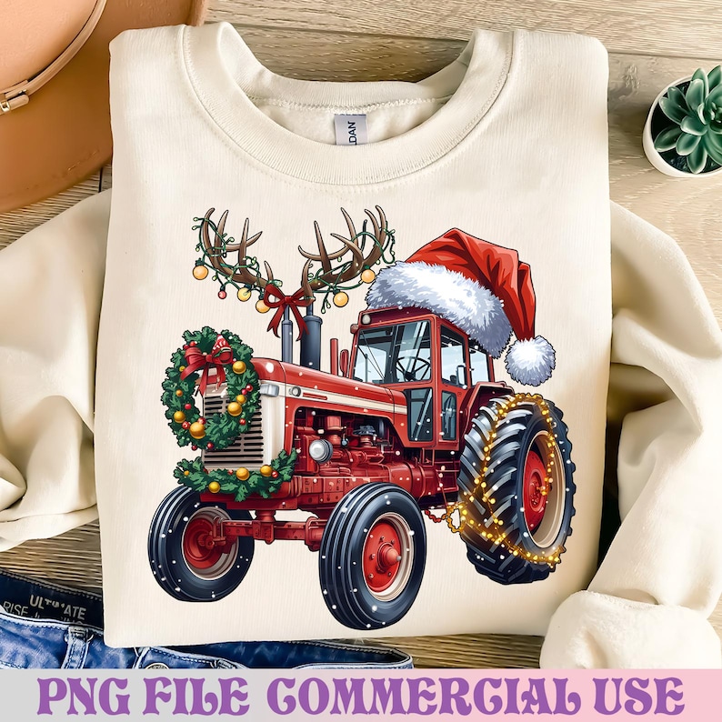 May include: Cream-coloured sweatshirt with a festive red tractor design. The tractor is decorated with a Santa hat, antlers, and a wreath, with string lights on the wheels. The text at the bottom reads "PNG FILE COMMERCIAL USE."