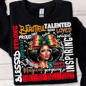 Op de afbeelding: Zwart sweatshirt met een afbeelding van een vrouw met een strik en bril. Het ontwerp bevat woorden als "Beautiful", "Talented", "Independent" en "Blessed" in verschillende lettertypen en kleuren.
