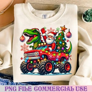 May include: Cream-colored sweatshirt featuring a festive design. A red monster truck is driven by Santa Claus, with a green dinosaur and Christmas tree in the truck bed. The truck is decorated with Christmas lights and ornaments. Text at the bottom reads "PNG FILE COMMERCIAL USE."