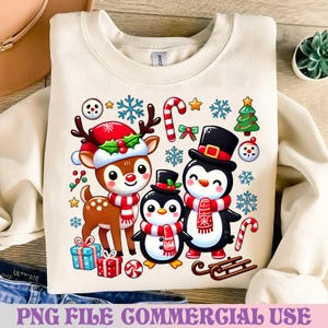May include: Cream-colored sweatshirt featuring a festive Christmas design. The graphic includes a reindeer wearing a Santa hat, two penguins, snowflakes, candy canes, and gift boxes. The text "PNG FILE COMMERCIAL USE" is at the bottom.