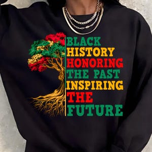 May include: Black sweatshirt with a tree graphic in red, yellow, and green. Text on the right reads "BLACK HISTORY HONORING THE PAST INSPIRING THE FUTURE" in green, red, and yellow.