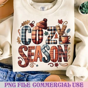 May include: Cream-colored sweatshirt with the words "COZY SEASON" in a plaid design. The design includes a knit cap, a coffee cup, and autumn leaves. The phrase "PNG FILE COMMERCIAL USE" is at the bottom.