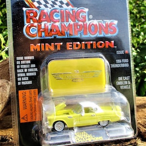 May include: A yellow 1956 Ford Thunderbird die-cast car model in a plastic package. The package has the words "Racing Champions Mint Edition" on it. The car has a white roof and a die-cast emblem.